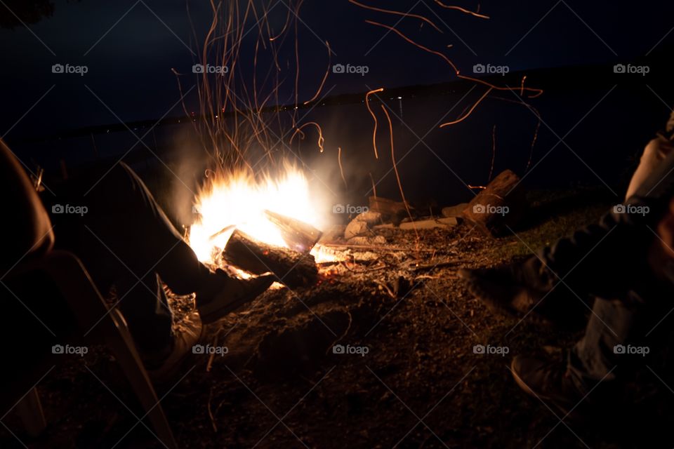 Friends sitting around a campfire at the lake 