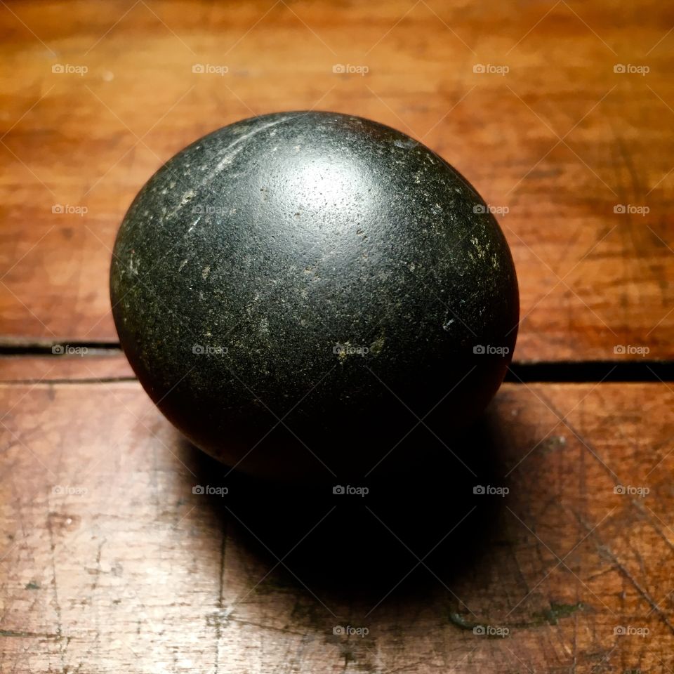 Round dark stone on wood table.