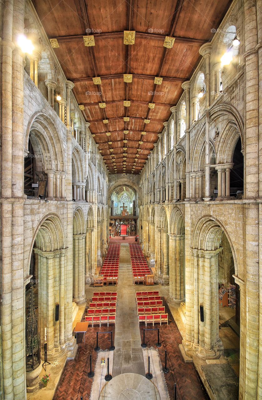 An interior view of a cathedral with large stone pillars and wooden ceiling.
