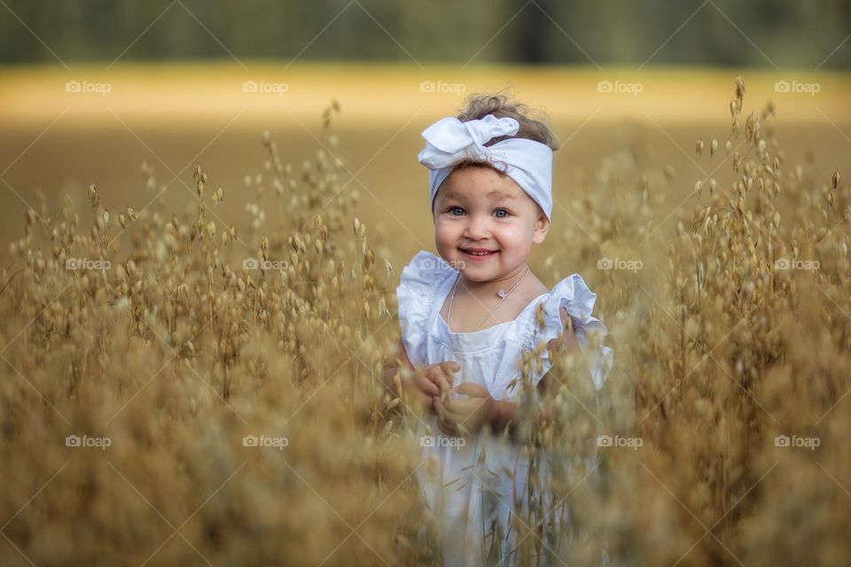 Little girl in rye field at summer evening 