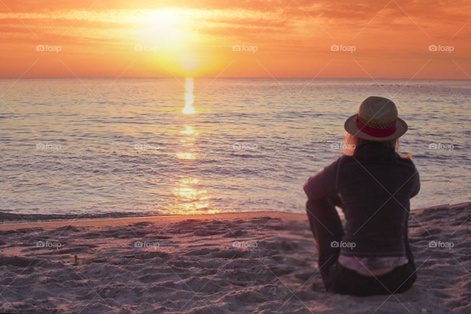 Woman watching the sunset into the ocean.