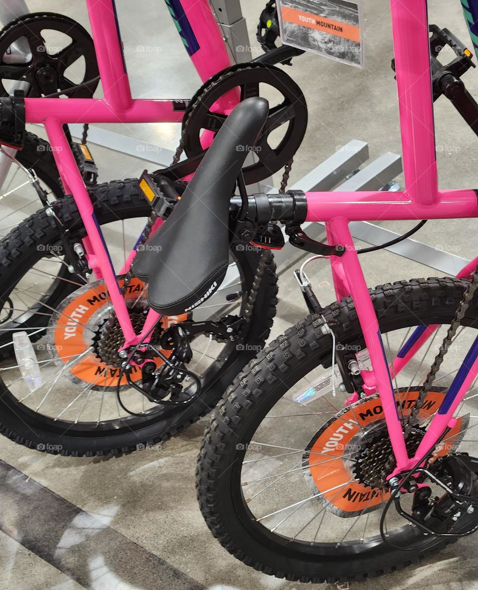 two bright 90s barbie style neon pink mountain bikes for sale in an Oregon sporting goods store