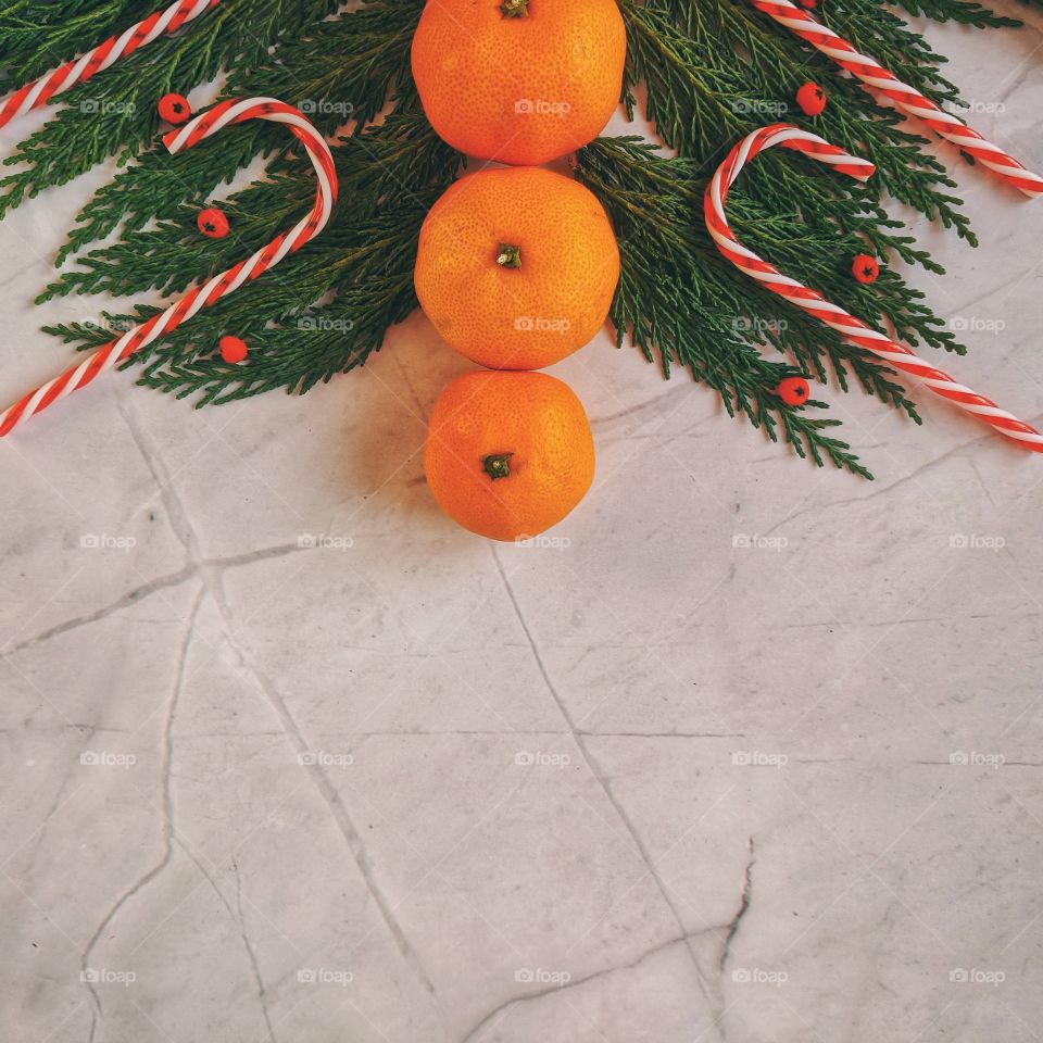 Christmas and New Year background with spruce branch, candies, decorations and tangerines Flat lay. Top view.