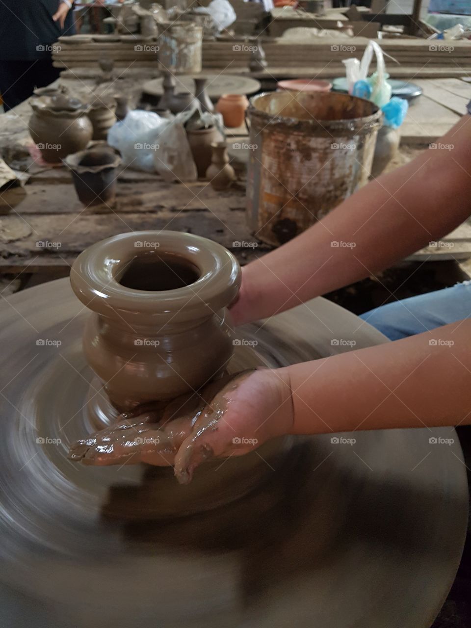 close of kid's hands practicing on clay to make pottery