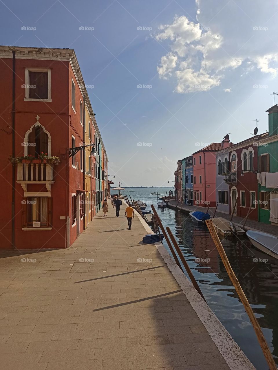 Sunny day in the city on the water. Venice. Burano. A man is walking. Sun, bright colors, beauty