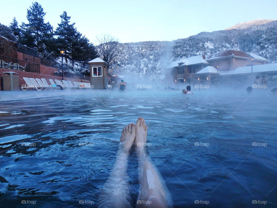 Enjoying hot spring in outdoor swimming pool in winter. Glenwood Springs, Colorado, with snow covered mountains as background.