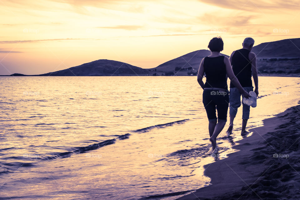 Senior Couple Walking On The Beach At Sunset
