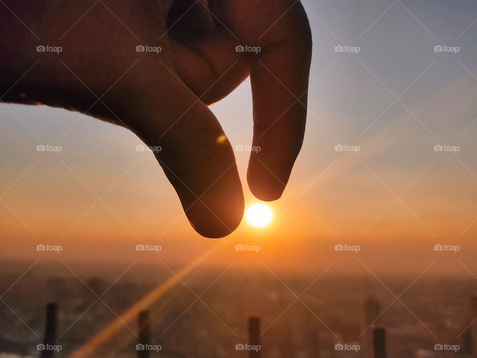 conceptual photo holding the sun between my fingers above Cairo tower the highest tower at the capital of Egypt, Cairo