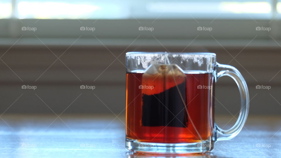 Teabag in a glass mug set near window