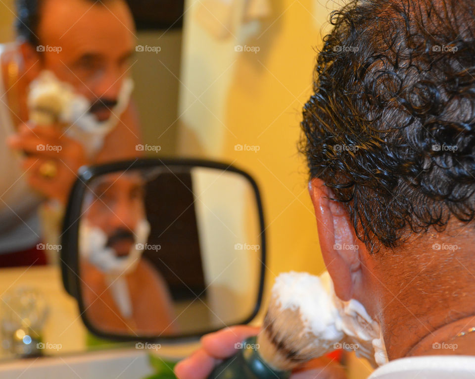 Portrait of a mature man shaving his beard