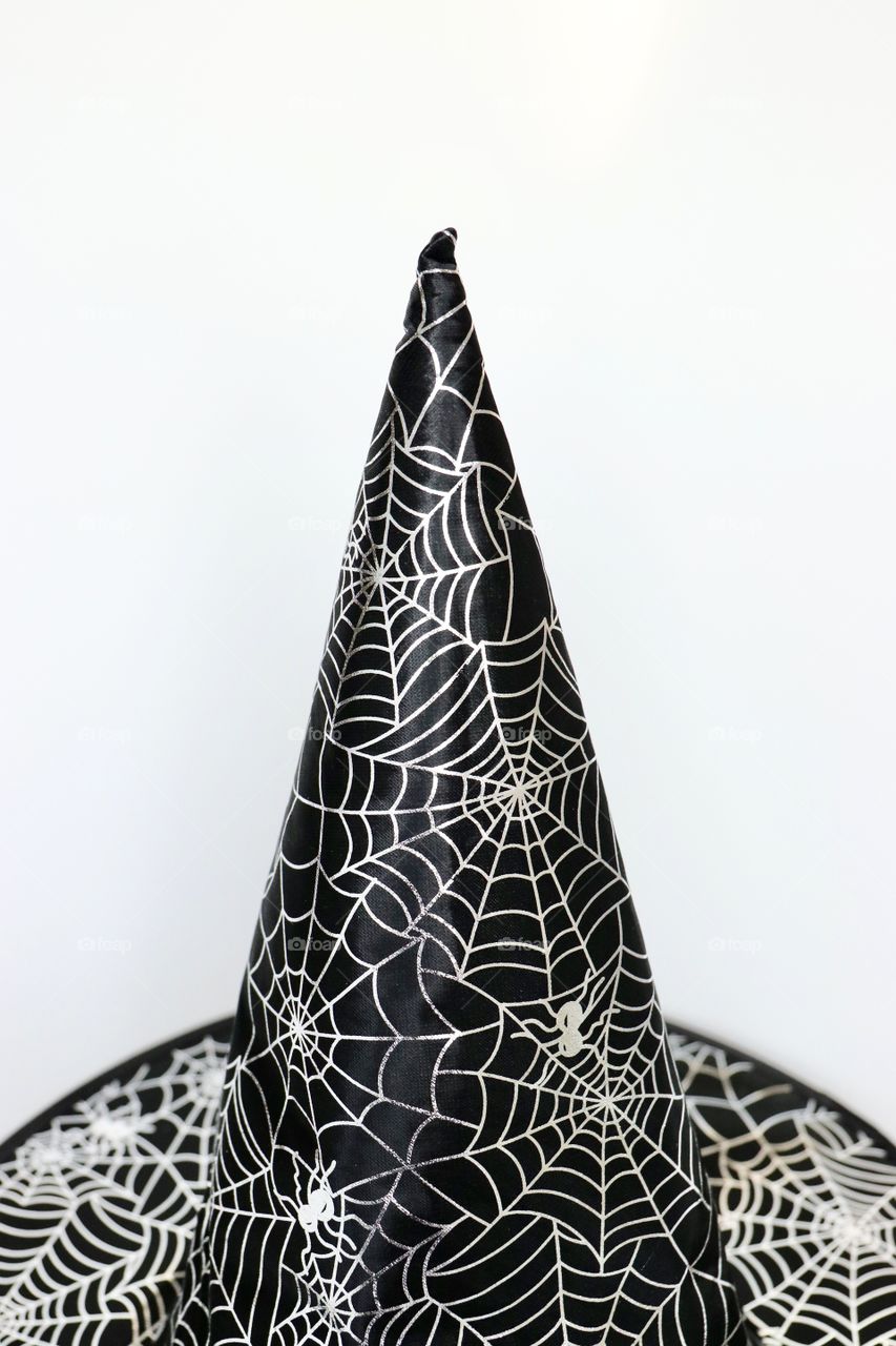A black hat with print of spider and net for Halloween, isolated, white background 