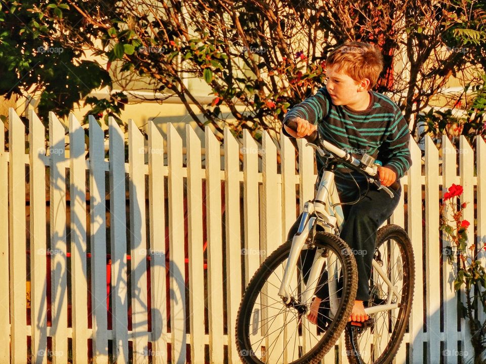 Biking In The Golden Hour. Boy Riding A Bike In A Residential Neighborhood At Sundown
