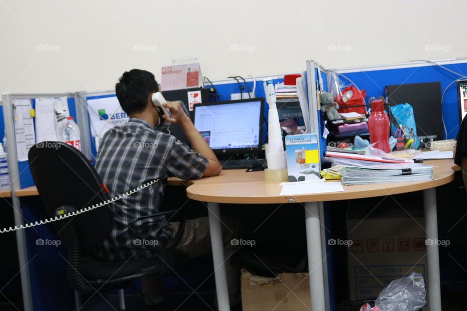 an asian worker takes a call in an office