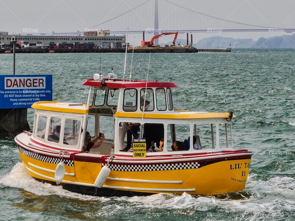 Yellow checkered water taxi transporting passengers from one point in San Francisco to another on the waters of the San Francisco Bay 