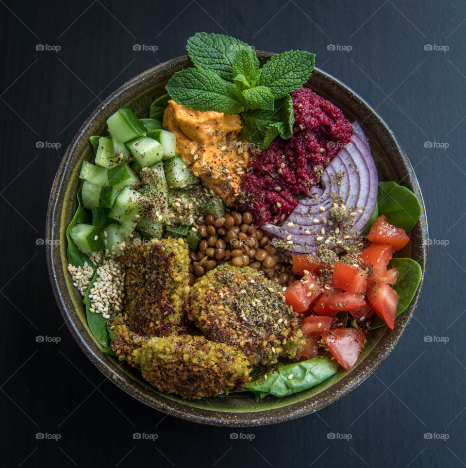 Falafel bowl with homemade falafels, tomatoes, red onion, lentils, mint, hummus and cucumber 