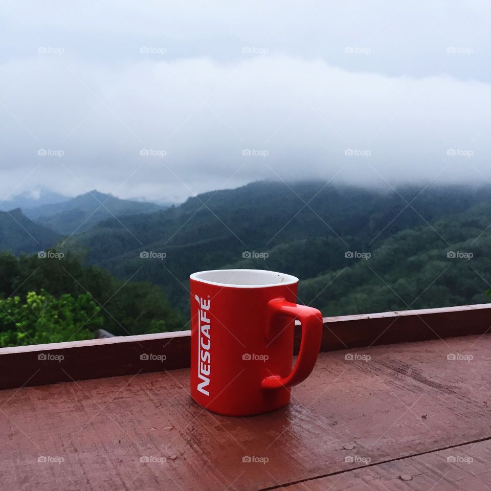 Red cup on table against mountain and forest