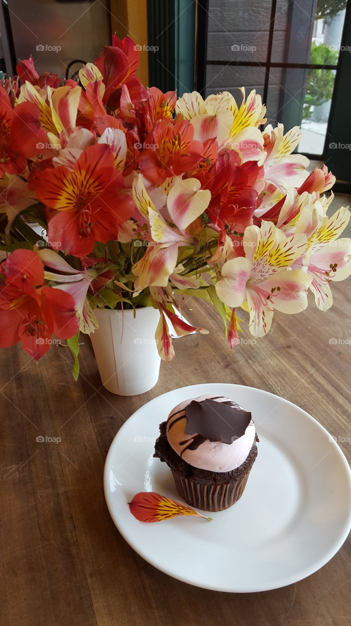 Cupcake and flower vase on wooden table