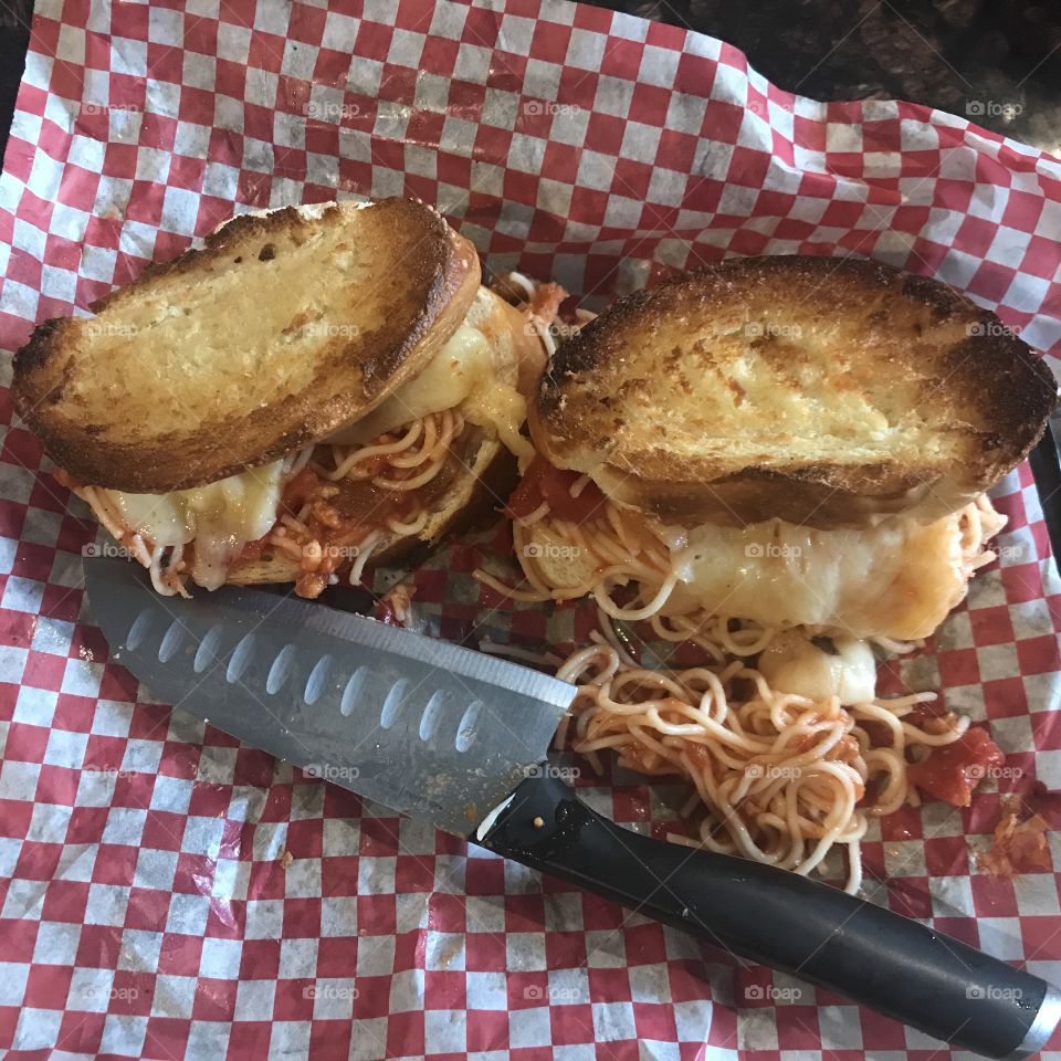 Spaghetti and cheese sandwiches served on a red and white checkered paper sandwich wrap. 