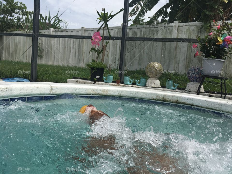 Dog playing with an orange ball at the pool
