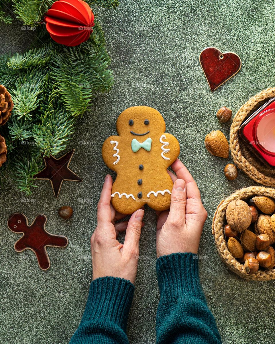 Female hands holding gingerbread man, top view