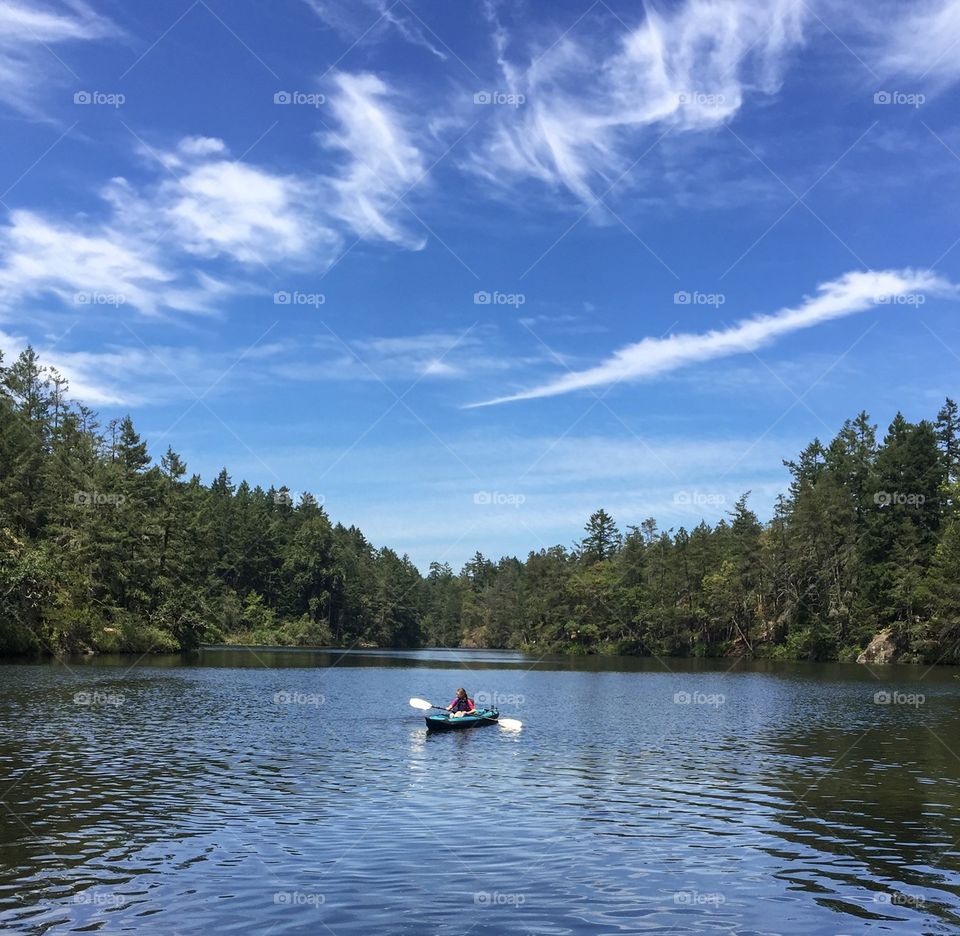 Kayaking in pristine lake under bright blue sky - summer fun