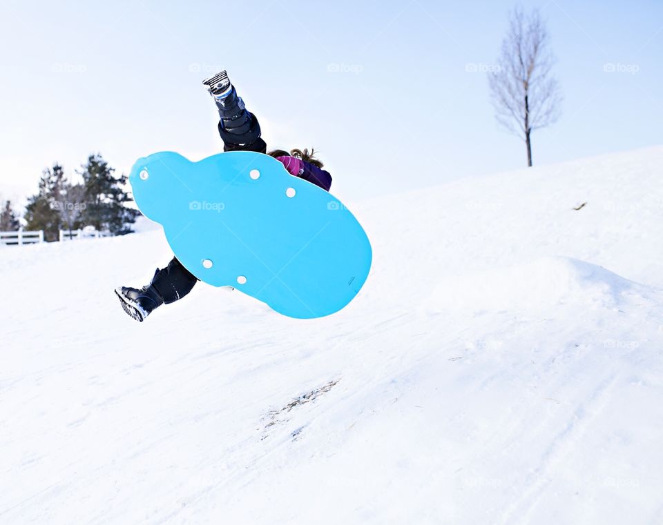 Girl flying through the air on a snow sled 