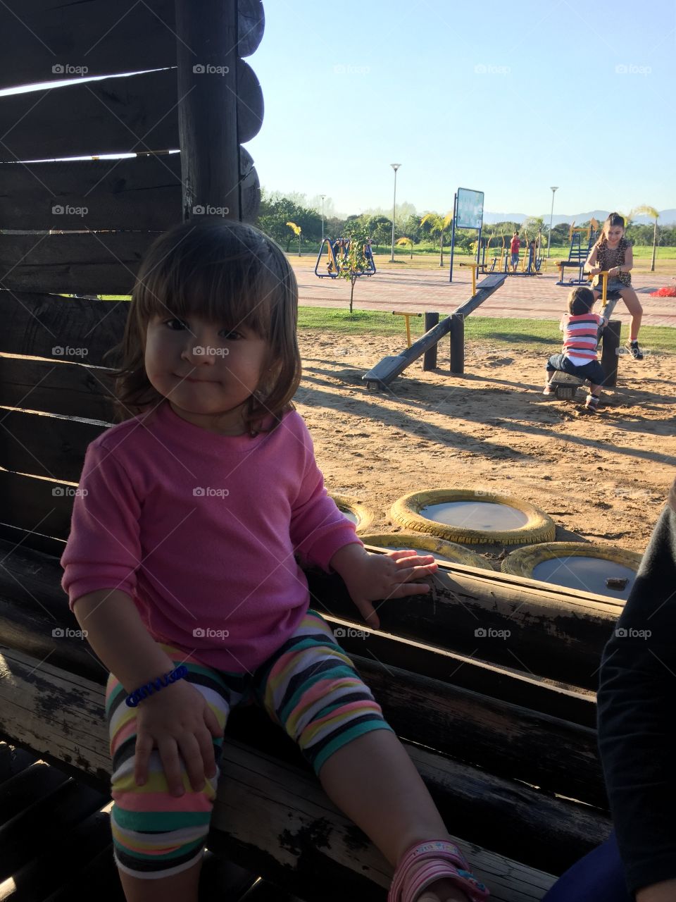 Little girl sitting in log house at playground