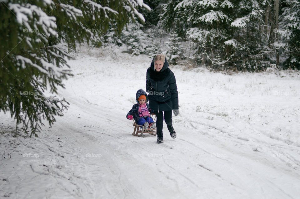 mom and doughter having fun riding down the hill with slegde