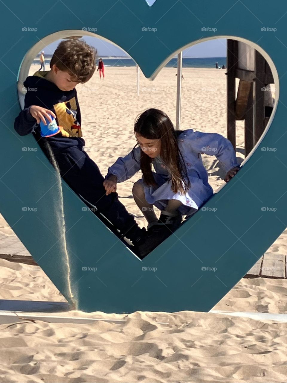 Children playing with sand in a heart
