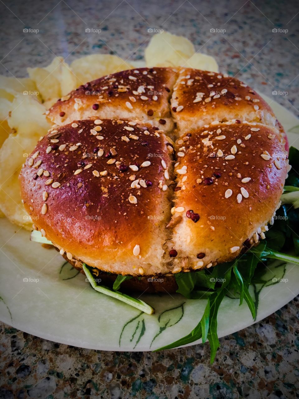 Grilled chicken sandwich with sesame seed  bun and potato chips on a plate 