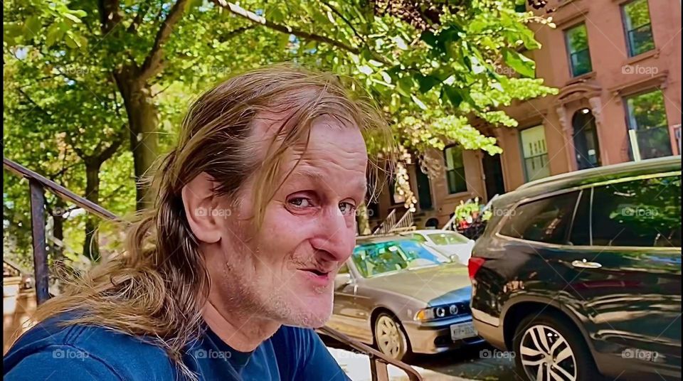 My life partner for nearly 16 years, “Timothy Trespas” is sitting on our favorite stoop on “Waverly St” off “Fulton St” in “Clinton Hill”, Brooklyn. This city block has beautiful lush green vegetation. 2022. Hypnotic Productions