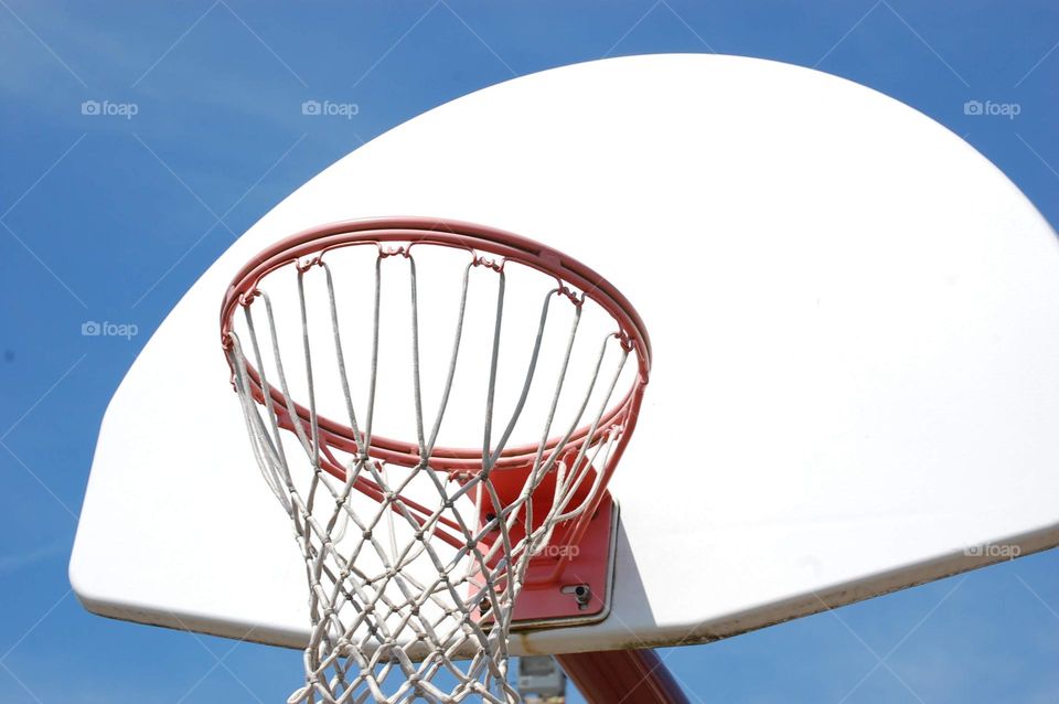 Basketball hoop against a bright blue sky 