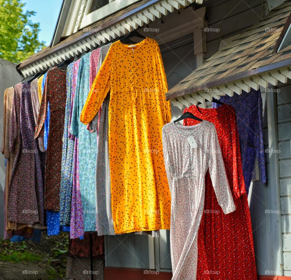 multi-colored dresses hang under the roof of the house developing in the wind