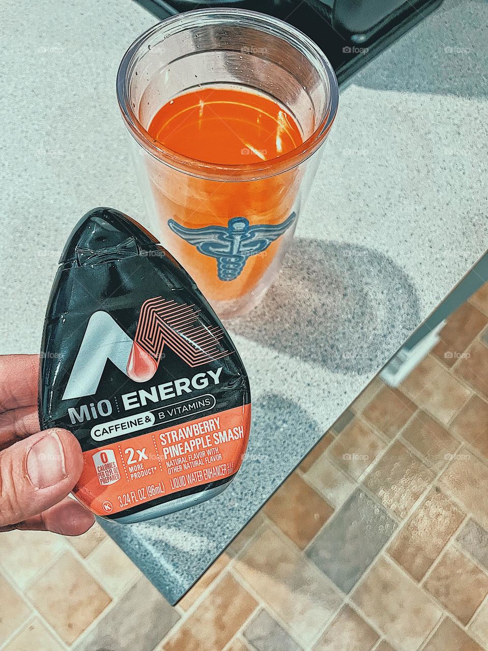 Woman making a Mio Energy water drink, woman using Mio Energy water drops to make a drink in a glass, making a healthy summertime drink, woman’s hand holding Mio Energy water drops, H2O Energy drops, healthy caffeine alternatives 