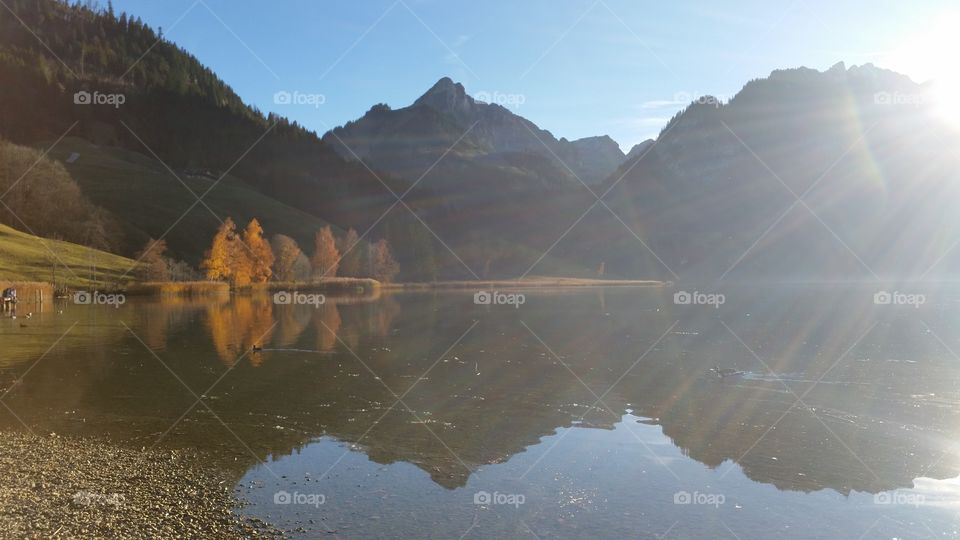 reflections and the sun on a lake in the swiss alps
