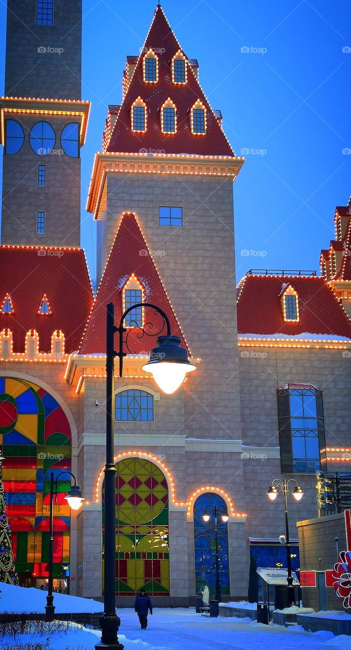 "Dream Island"  Thematic game complex.  Winter view, evening.  Near view of one of the towers of the complex with illumination.  A lantern is lit in the foreground