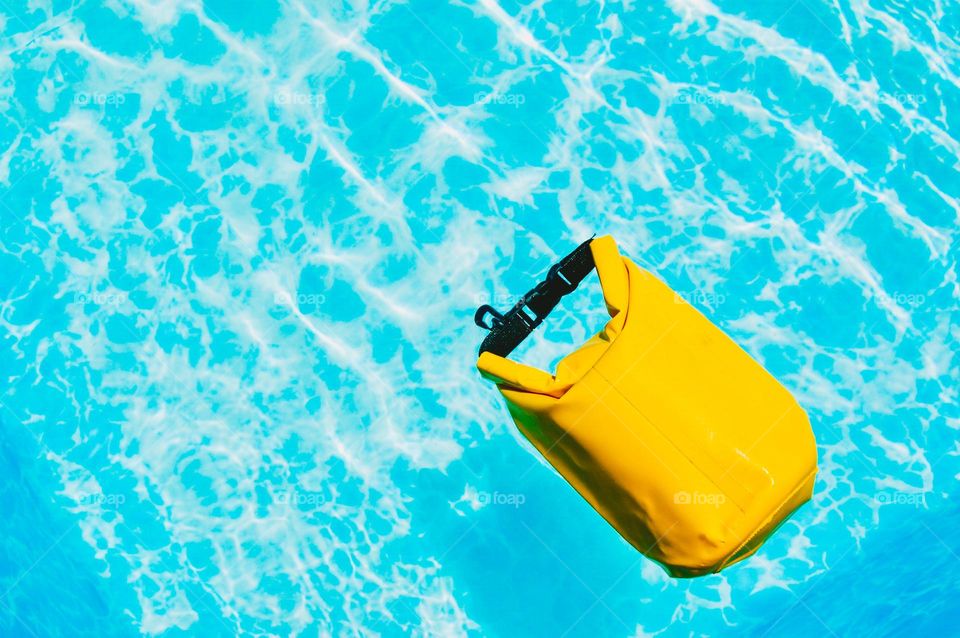 Yellow dry bag floating in swimming pool 