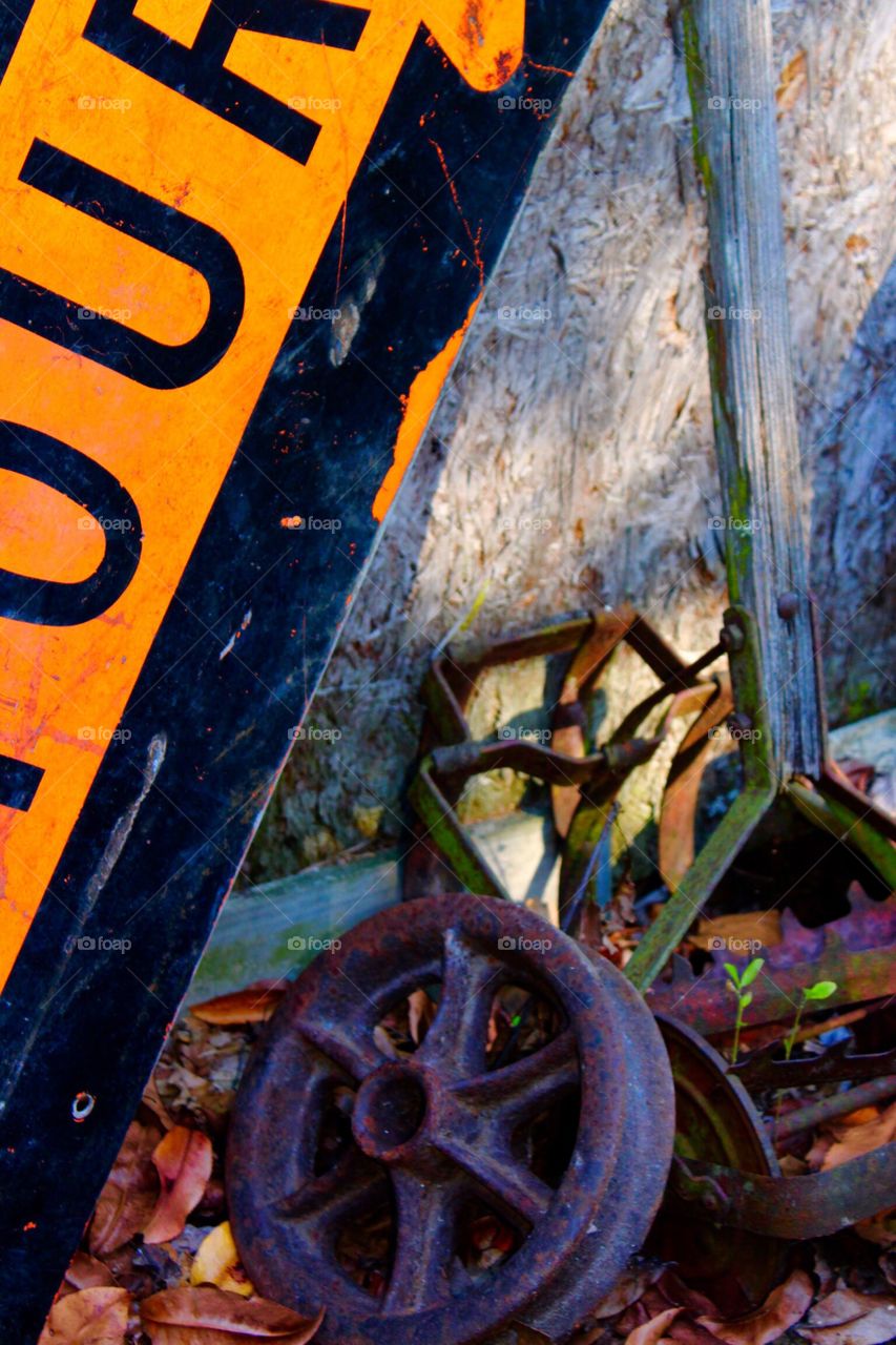 Detour sign and gear next to rusty parts in back of a garden shed