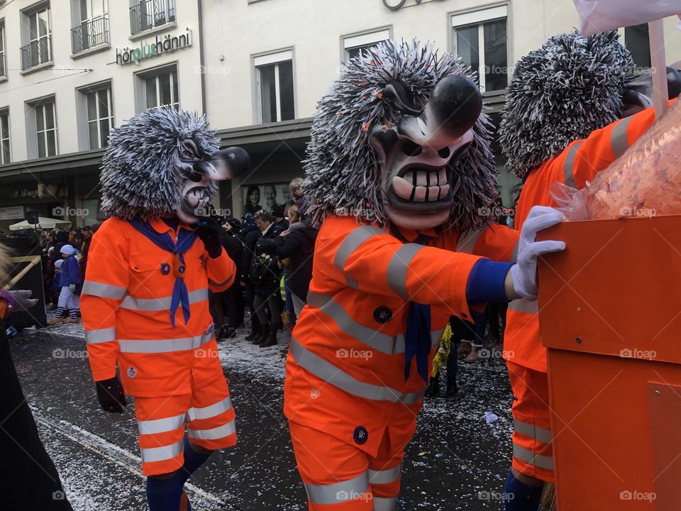 a large crowd of people running in the city among large buildings. a crowd of people in masquerade costumes and masks at a fundamental festival in Switzerland. people in bright costumes on a holiday
