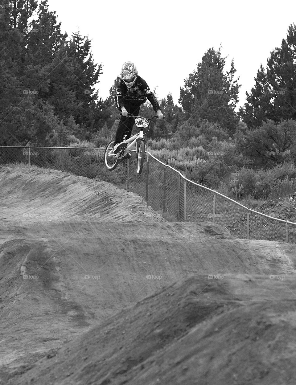 A BMX racer flies off a berm high into the air. 