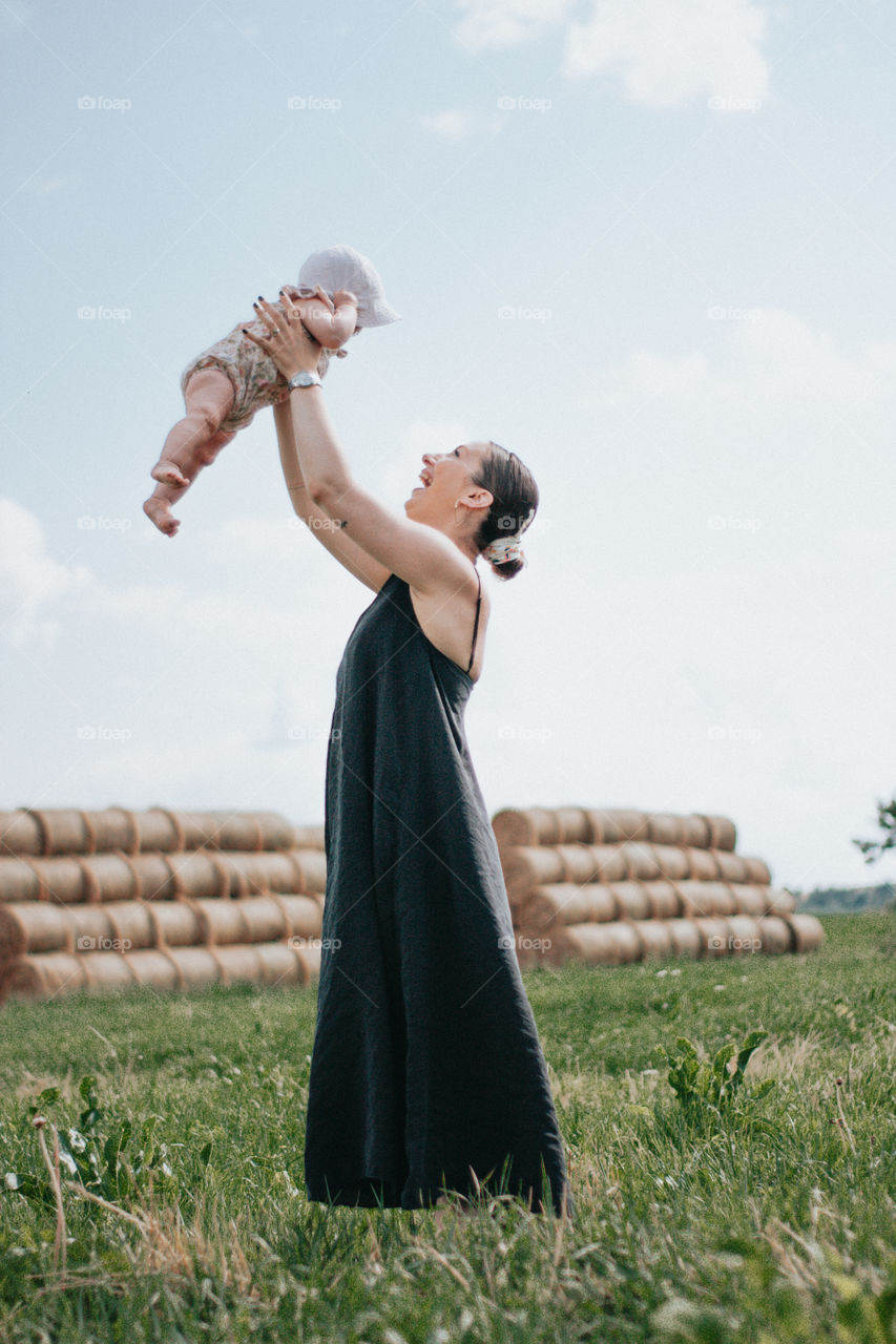 mother holding her daughter up in the air while smiling at her