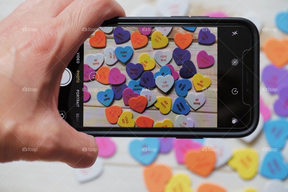 People on their phones, woman taking pictures with phone, taking picture of hearts with phone, iPhone photography, picture of a picture, people using their phones, creating with your phone 