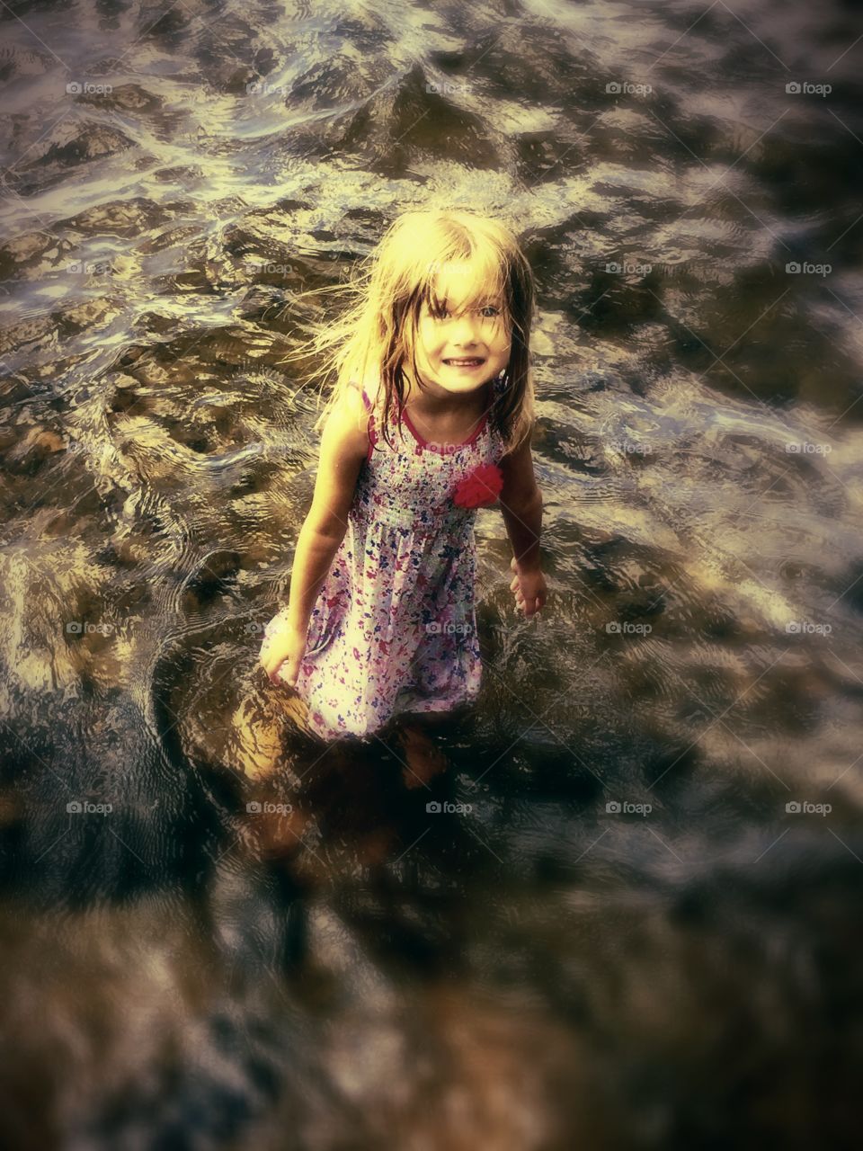 Cute small girl standing in river