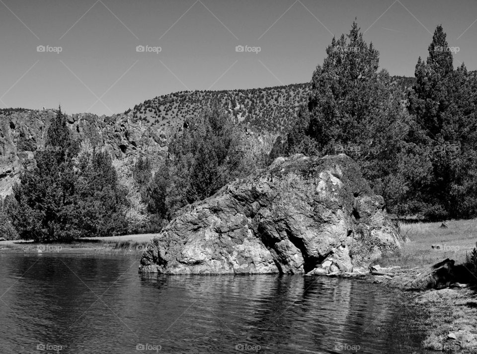 A giant boulder among the juniper trees on the shore at Prineville Reservoir on a sunny summer morning 