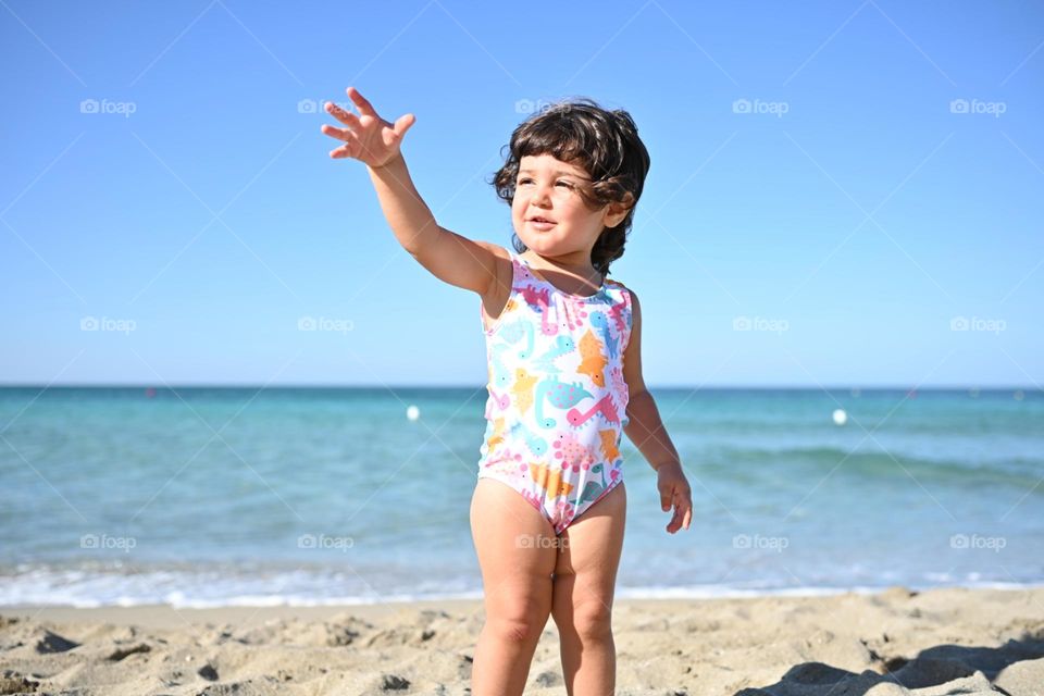 little girl on the beach watching the seagulls