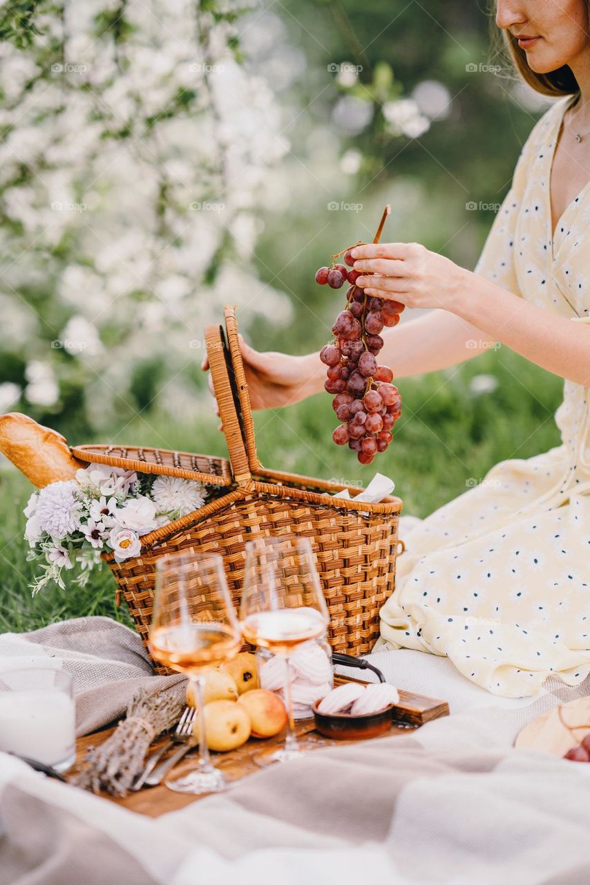 Woman takes out grapes from a basket. Picnic in public park