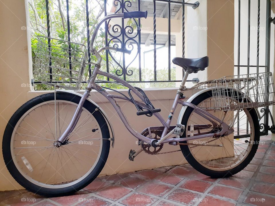 A lilac colored bicycle sits propped up against a window of an office complex in Central Florida.