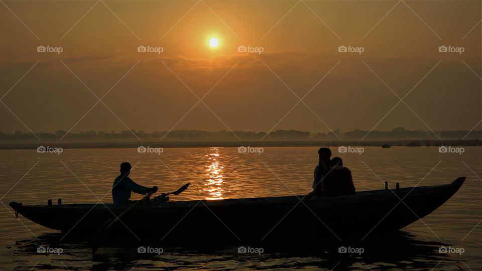 Sunrise over the river Ganges in India with a silhouette boat.