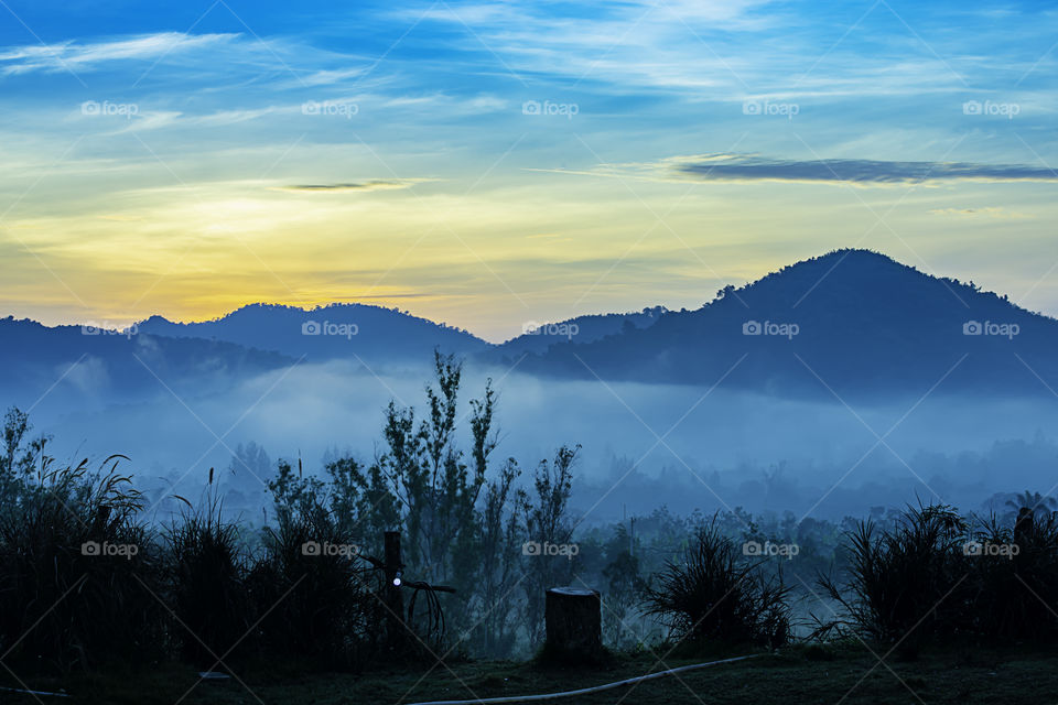 The morning sun behind the mountain and fog covering the trees.