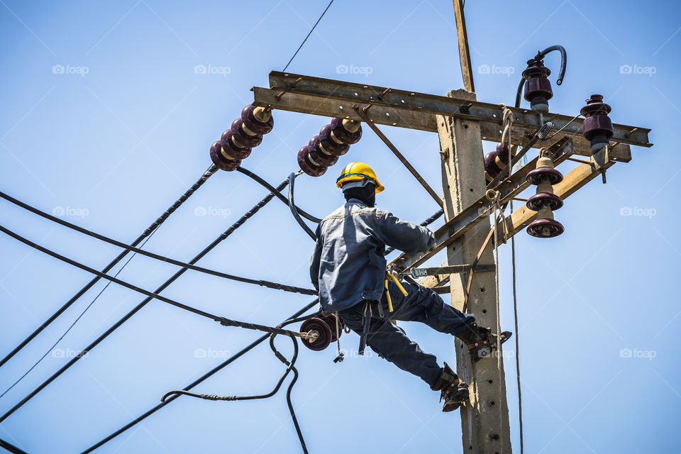 Electrician working on the electricity pole to replace the electrical insulator